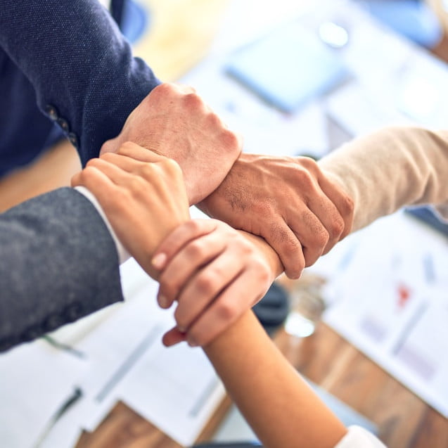 Four people grab each other's wrists to create a square, a visual metaphor for how our team works with you to build a Cadent website.